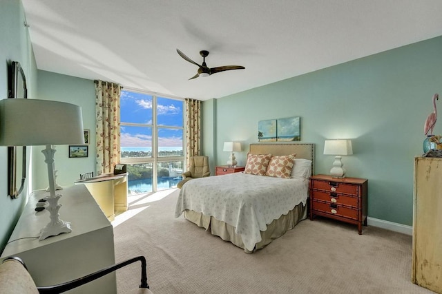 carpeted bedroom featuring access to outside, floor to ceiling windows, ceiling fan, and a water view