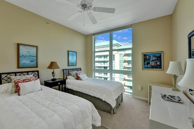 bedroom with multiple windows, ceiling fan, and light colored carpet