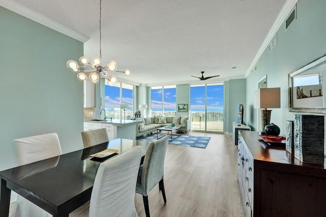 dining area with plenty of natural light, ornamental molding, ceiling fan with notable chandelier, and light hardwood / wood-style flooring