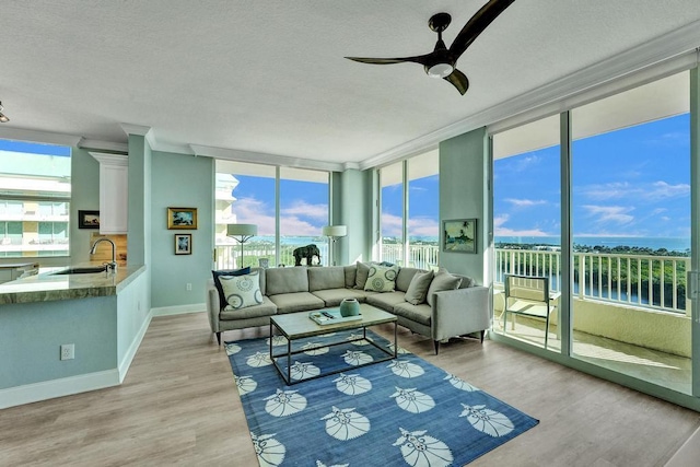 sunroom with a water view, ceiling fan, a healthy amount of sunlight, and sink