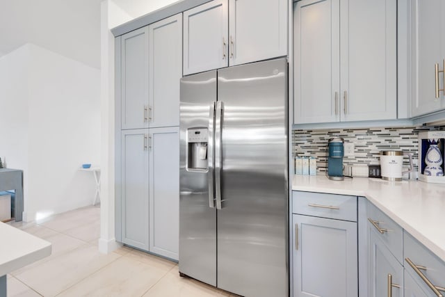 kitchen featuring backsplash, stainless steel refrigerator with ice dispenser, light countertops, and gray cabinetry