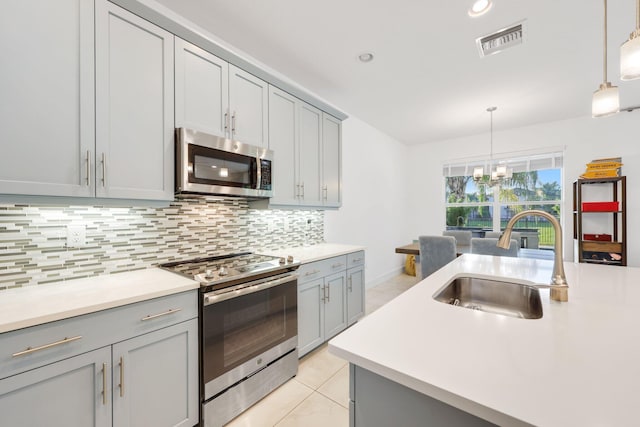 kitchen with appliances with stainless steel finishes, gray cabinets, visible vents, and a sink