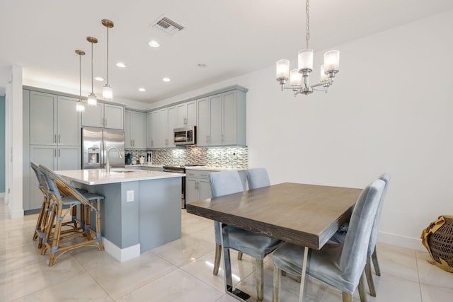 kitchen featuring appliances with stainless steel finishes, gray cabinetry, tasteful backsplash, hanging light fixtures, and a chandelier