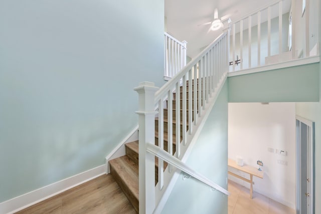 stairway with a ceiling fan, baseboards, and wood finished floors