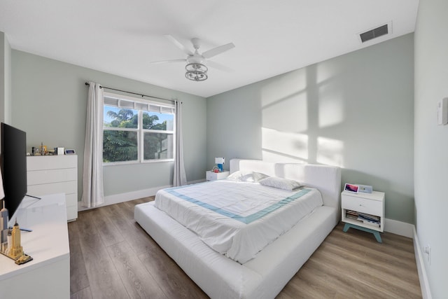 bedroom featuring baseboards, visible vents, ceiling fan, and wood finished floors