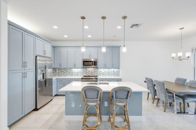 kitchen featuring appliances with stainless steel finishes, sink, a center island with sink, and decorative light fixtures