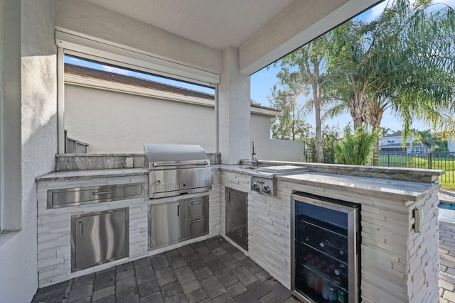 view of patio featuring beverage cooler, fence, an outdoor kitchen, and area for grilling