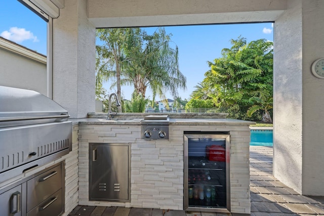 view of patio / terrace with area for grilling, exterior kitchen, sink, a swimming pool, and beverage cooler