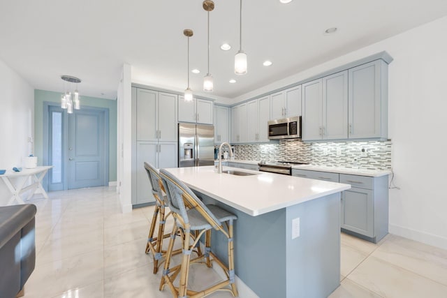 kitchen with backsplash, stainless steel appliances, a sink, and gray cabinetry