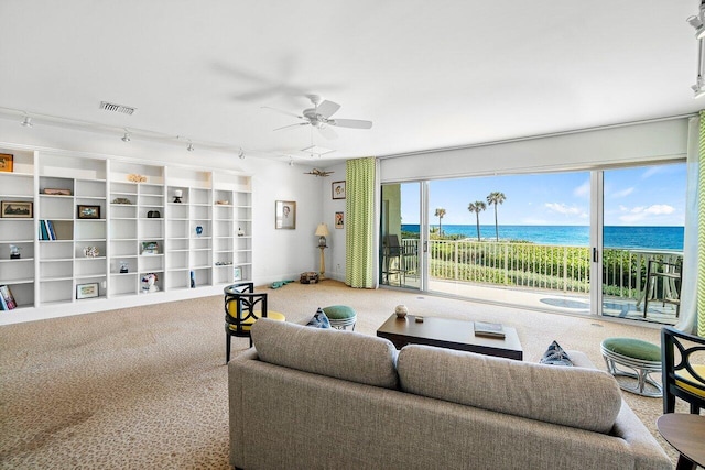 living room with carpet floors, ceiling fan, and a water view