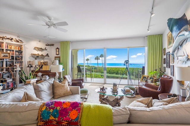 living room with ceiling fan, a water view, and track lighting