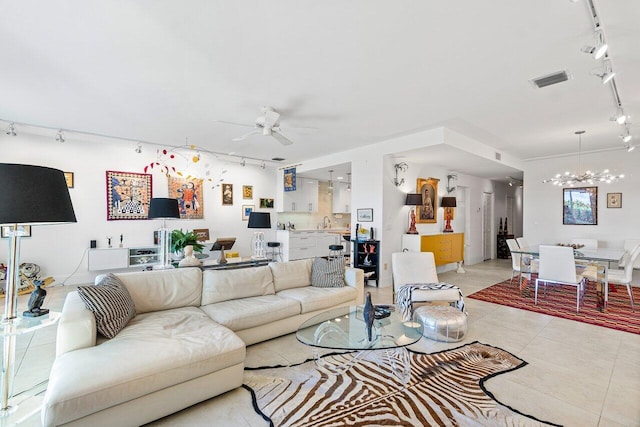 living room with ceiling fan with notable chandelier, light tile patterned flooring, sink, and rail lighting