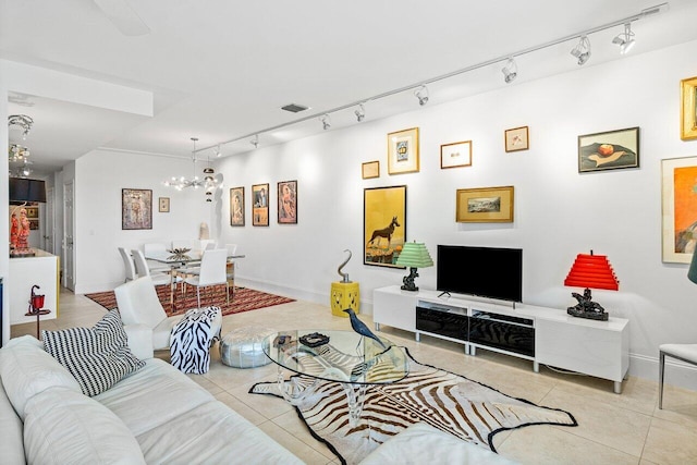 tiled living room featuring a notable chandelier and track lighting