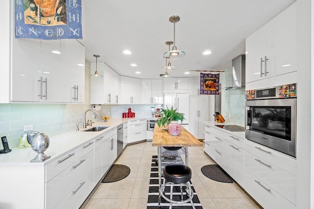 kitchen featuring wall chimney exhaust hood, stainless steel appliances, sink, white cabinets, and hanging light fixtures