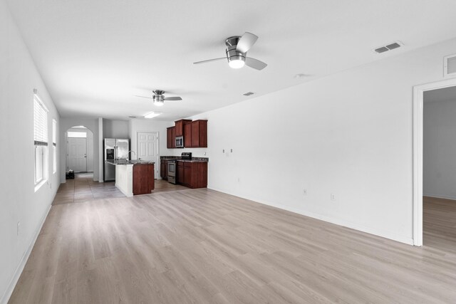 unfurnished living room featuring light carpet and ceiling fan with notable chandelier