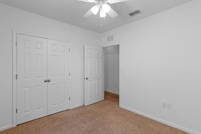 unfurnished bedroom featuring a closet, light colored carpet, and ceiling fan