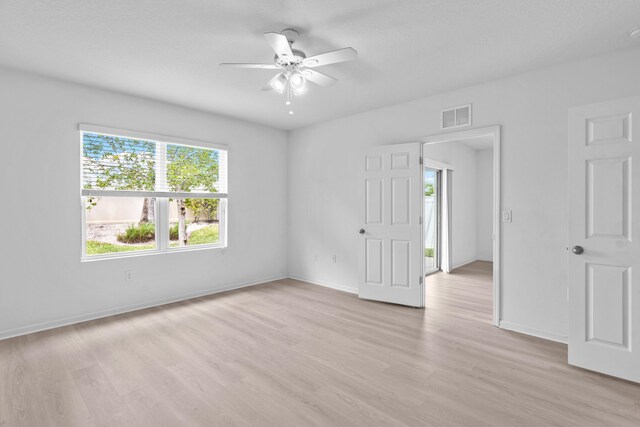 unfurnished bedroom with ensuite bath, ceiling fan, a walk in closet, light carpet, and a closet