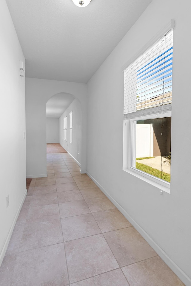 hall with light tile patterned flooring and a healthy amount of sunlight