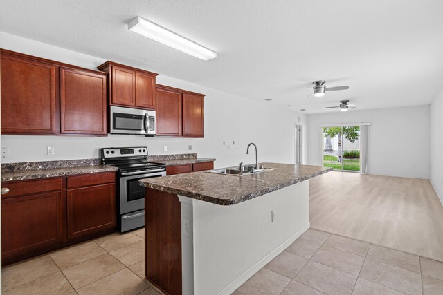 kitchen featuring sink, an island with sink, light carpet, ceiling fan with notable chandelier, and appliances with stainless steel finishes