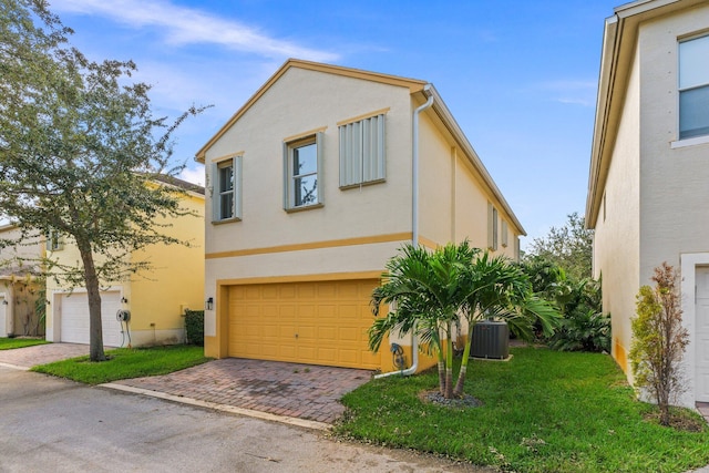 view of front facade with a front yard, central AC unit, and a garage