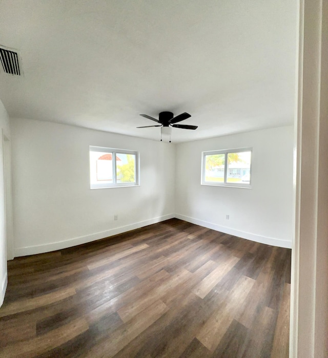 spare room with ceiling fan, plenty of natural light, and dark wood-type flooring