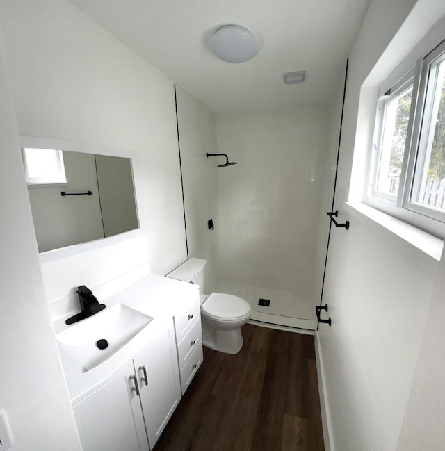 bathroom with a shower, vanity, hardwood / wood-style flooring, and toilet