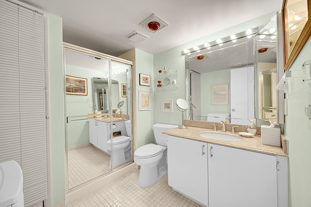 bathroom featuring tile patterned floors, vanity, toilet, and an enclosed shower