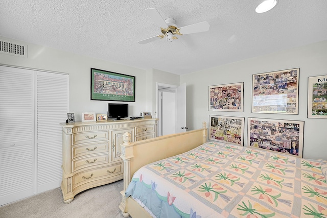 bedroom featuring a textured ceiling, a closet, ceiling fan, and light colored carpet