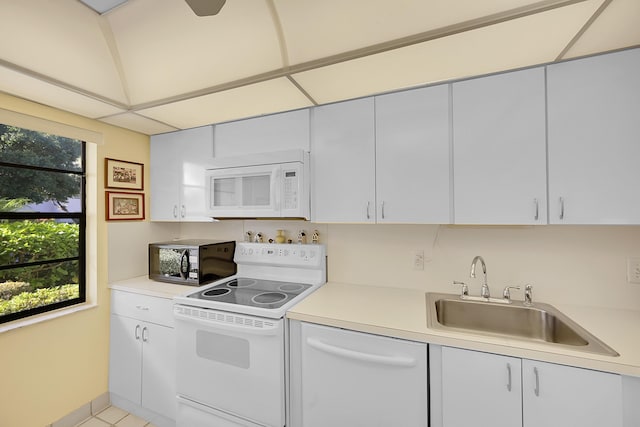 kitchen featuring white cabinets, light tile patterned floors, white appliances, and sink