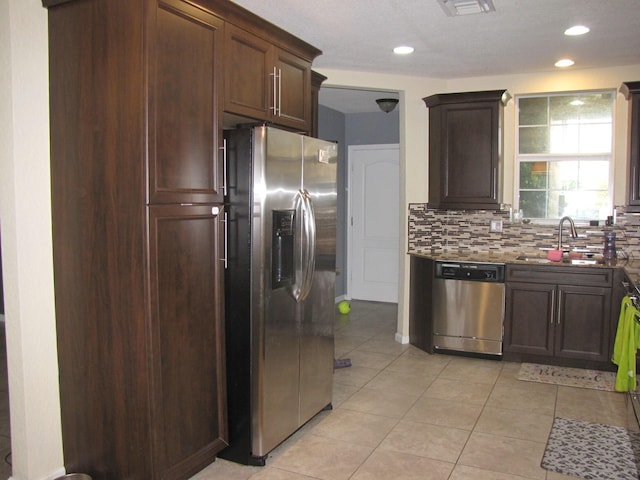 kitchen featuring sink, tasteful backsplash, dark brown cabinets, light tile patterned flooring, and stainless steel appliances