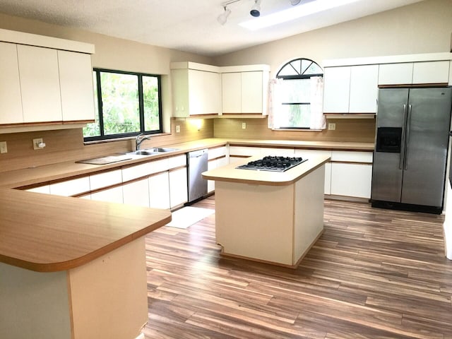 kitchen with hardwood / wood-style floors, a kitchen island, white cabinetry, and appliances with stainless steel finishes