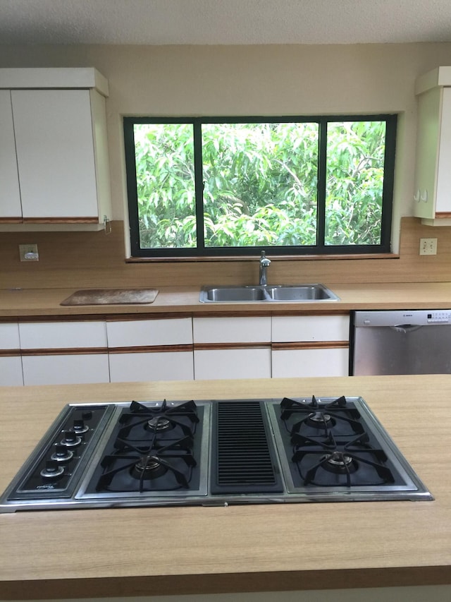 kitchen featuring a wealth of natural light, dishwasher, white cabinets, and sink