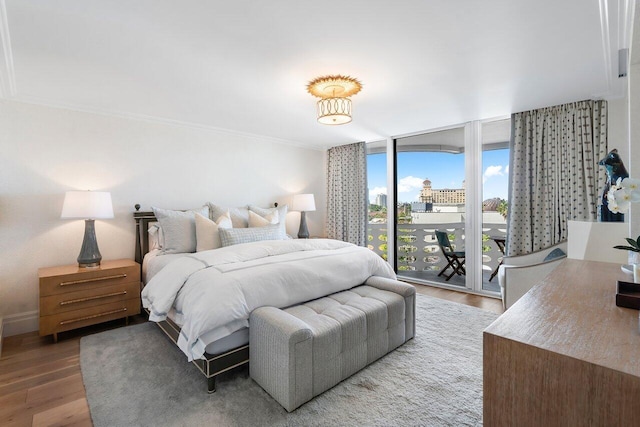 bedroom with access to exterior, hardwood / wood-style flooring, a wall of windows, and crown molding