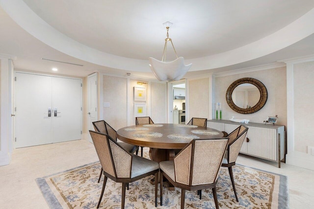 dining space featuring a raised ceiling and ornamental molding