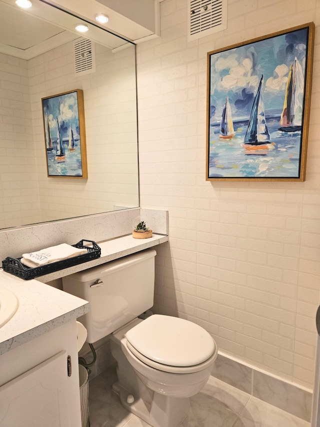 bathroom featuring vanity, toilet, and tile walls