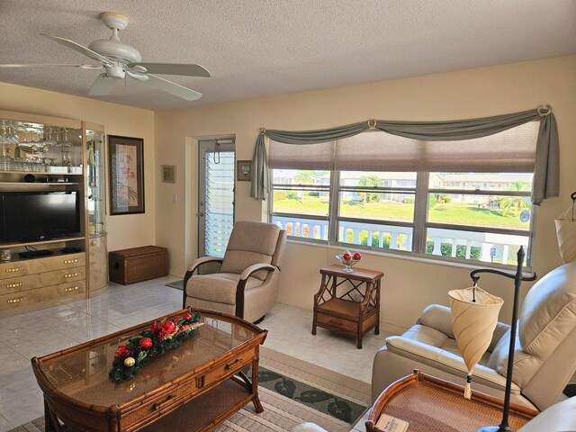 tiled living room with ceiling fan and a textured ceiling