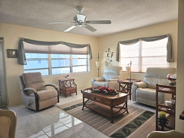 living room with ceiling fan, light tile patterned floors, and a textured ceiling