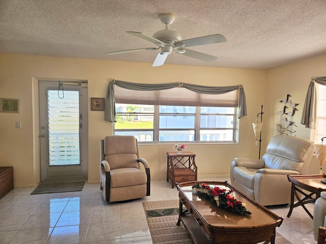 tiled living room with ceiling fan and a textured ceiling