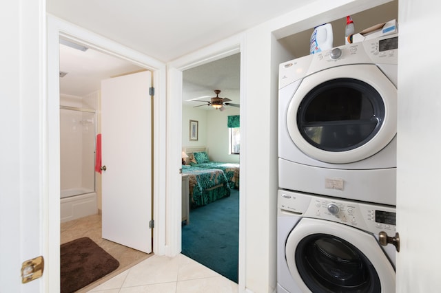 laundry area with ceiling fan, stacked washer / dryer, and light tile patterned flooring