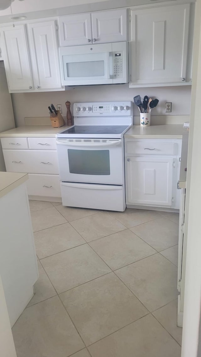 kitchen with light tile patterned flooring, white appliances, and white cabinetry