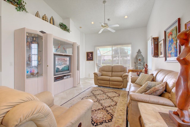 living room featuring ceiling fan, light tile patterned floors, a textured ceiling, and a high ceiling