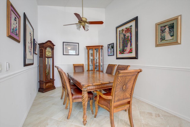 tiled dining space with ceiling fan and high vaulted ceiling