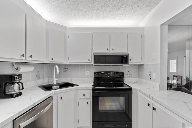 kitchen with light stone counters, sink, white cabinetry, and stainless steel appliances