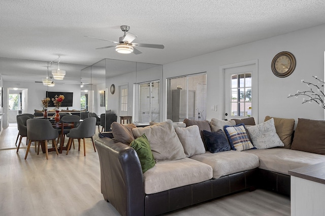 living room with ceiling fan, a healthy amount of sunlight, a textured ceiling, and light wood-type flooring