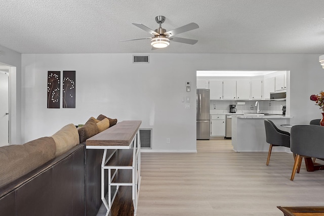 interior space featuring a textured ceiling, light hardwood / wood-style floors, and ceiling fan