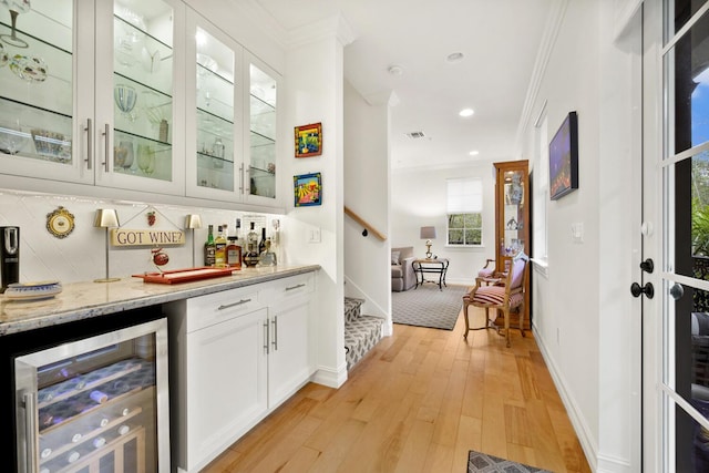 bar with white cabinetry, light stone countertops, tasteful backsplash, wine cooler, and light wood-type flooring