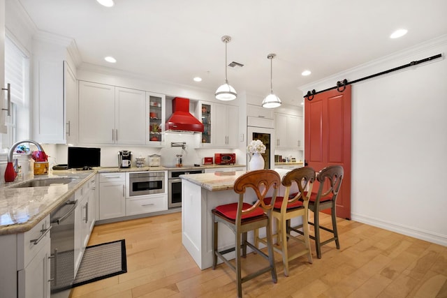 kitchen with custom exhaust hood, sink, a barn door, a kitchen island, and white cabinetry