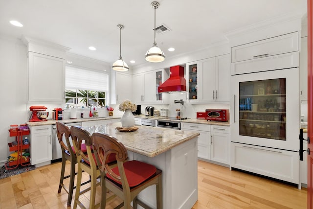 kitchen with light wood-type flooring, custom exhaust hood, a breakfast bar, a center island, and white cabinetry