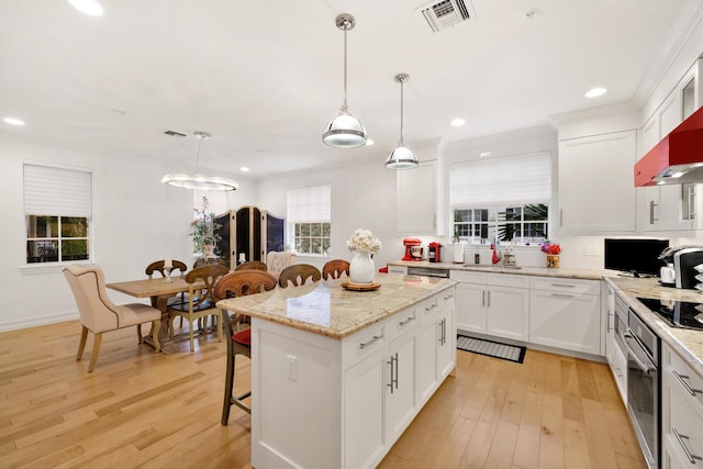 kitchen featuring white cabinetry, a kitchen island, light hardwood / wood-style floors, and decorative light fixtures