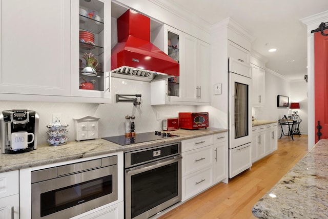 kitchen with white cabinetry, light hardwood / wood-style flooring, built in appliances, crown molding, and custom exhaust hood